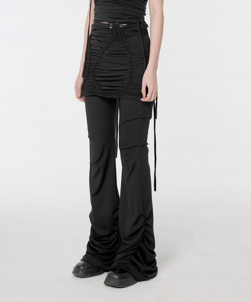 Waist down view of black outfit with ruched skirt and flare pants.