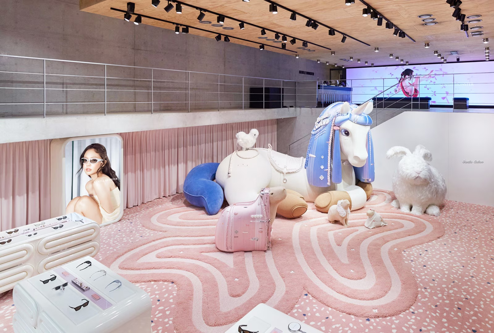 Room with pink flooring and rug, large unicorn sculpture, sunglass display cases, and other creative fixutres.