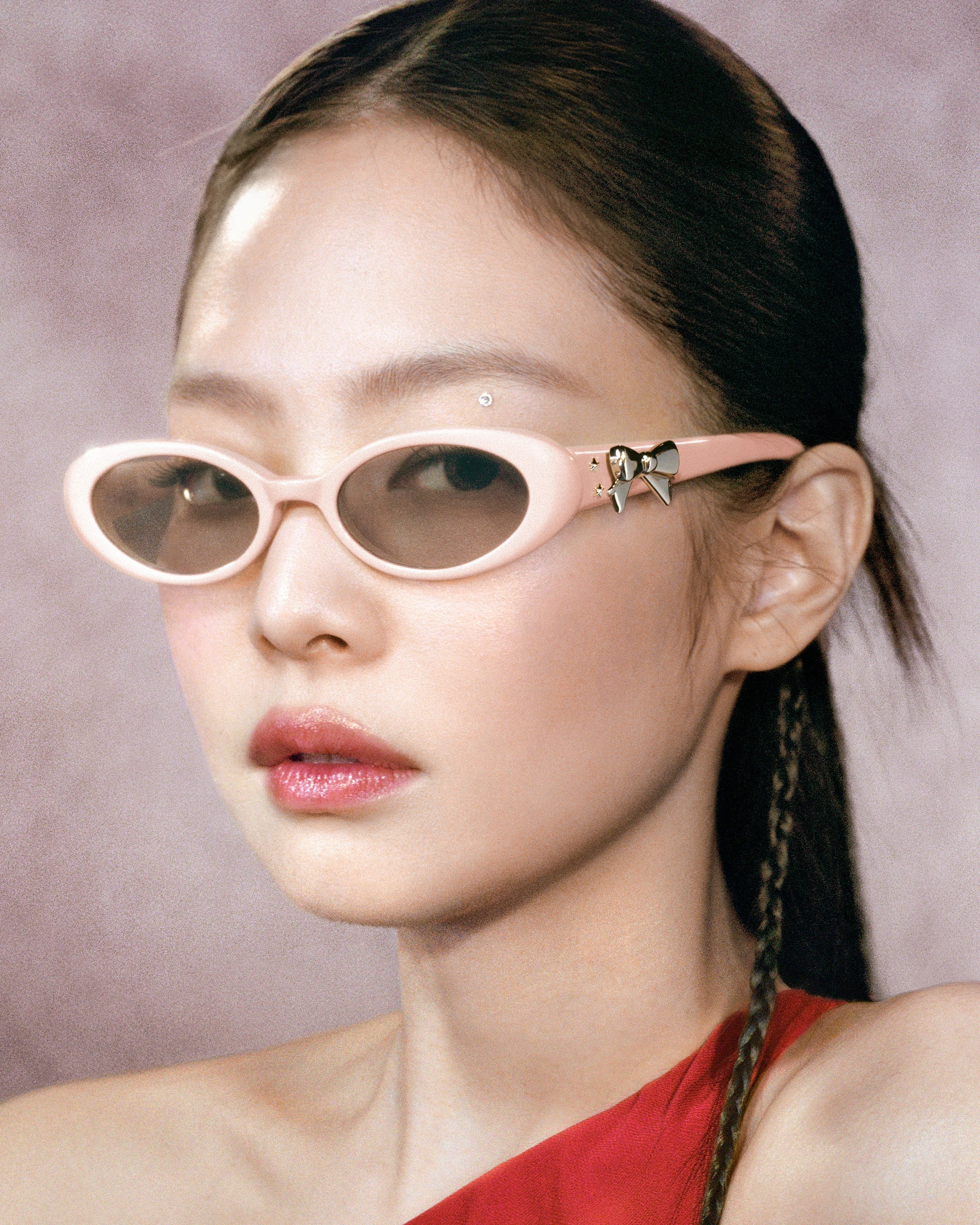 Close up of model's face wearing pink sunglasses with bow charm.