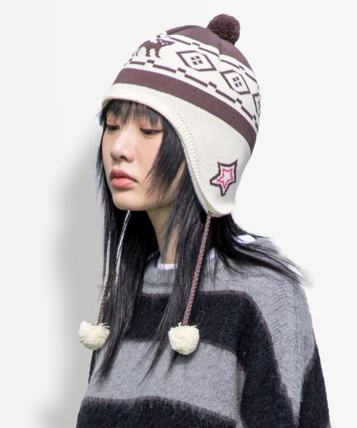 Girl wearing winter flap hat with pom poms.