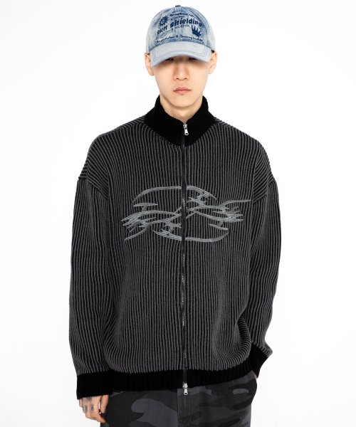 Male wearing denim hat and knitted zip-up sweaater with chrome accents.